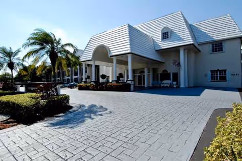 Front exterior of Veranda Club facility with an arched entrance and palm trees.