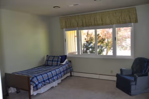Small bedroom with a single bed, blue plaid bedding, and a window view.