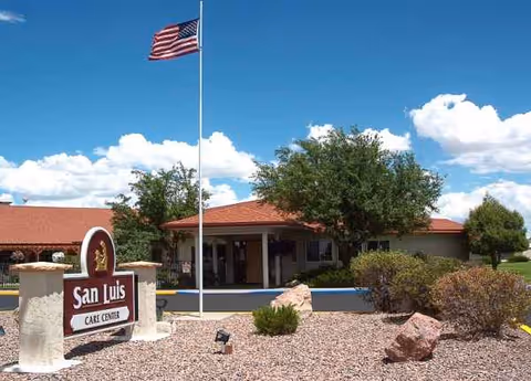 Exterior view of San Luis Care Center with sign, American flag, and entryway.