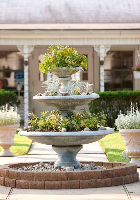 Stone fountain with potted greenery in a courtyard at Ashbrook Care & Rehabilitation Center.