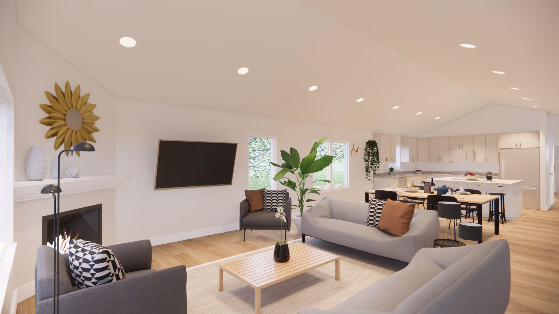A bright and spacious open-concept living area featuring modern furniture including two gray sofas, a gray armchair with patterned cushions, a wooden coffee table with a small plant, a wall-mounted flat-screen TV, and a fireplace with decorative items on the mantel. The room extends into a kitchen and dining area with white cabinetry, a dining table with black chairs, and large windows letting in natural light.