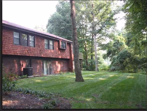 Exterior of a red-brick senior living building with a manicured lawn and trees.
