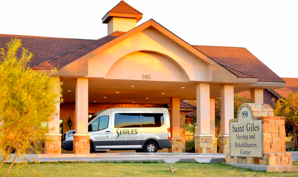 Exterior view of St. Giles Nursing and Rehabilitation Center showing the entrance with a covered drop-off area, a white shuttle van parked under the canopy, and a stone sign with the facility's name and address number 950.