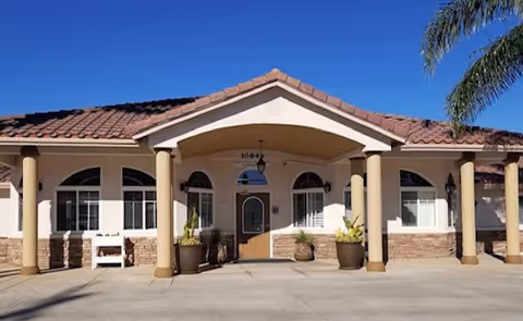 Front view of The Gardens of Riverside senior living facility with arches, columns, and planters.