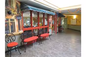 Indoor hallway/common area with red-cushioned benches, a green awning over windows, and a mural on the wall.