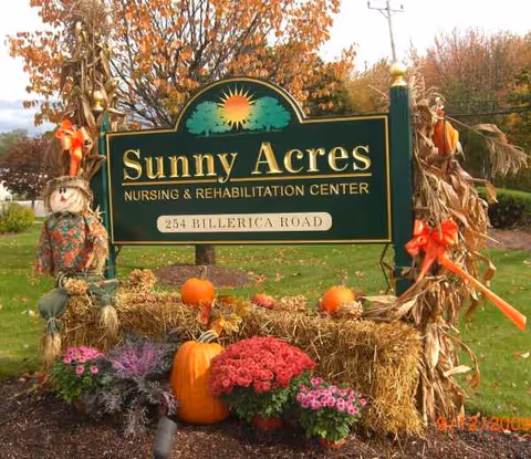 Sunny Acres Nursing & Rehabilitation Center sign with pumpkins and autumn flowers outside.