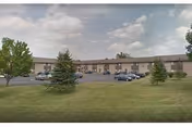 Exterior view of Sanderson Court Senior Apartments, a one-story brick building with cars.