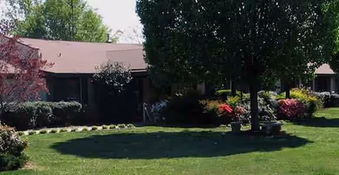 Exterior view of Powdersville Post-Acute with lawn, trees, and shrubs.