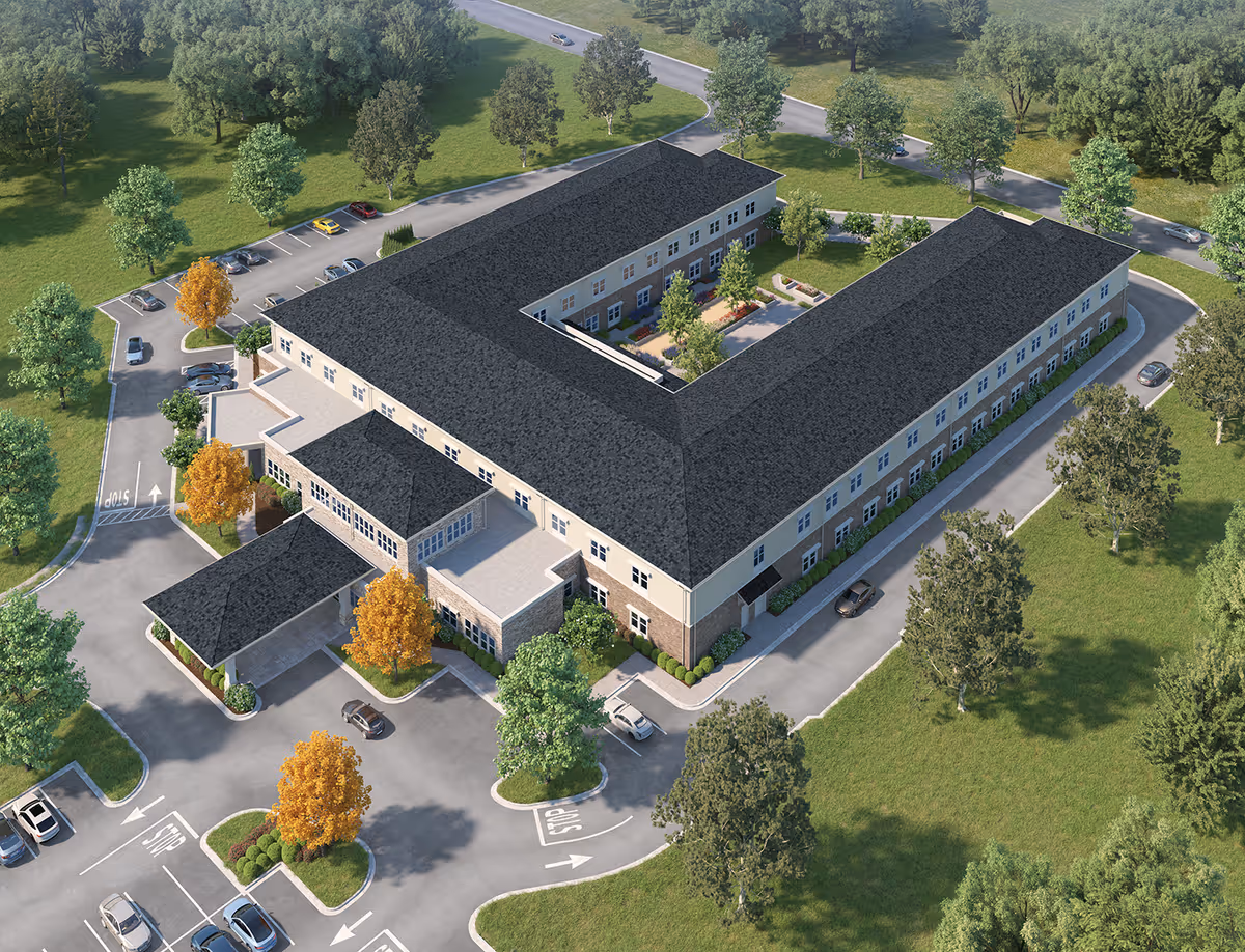 Aerial view rendering of a U-shaped three-story senior living building with a central courtyard, surrounding parking, driveways, and landscaped trees.