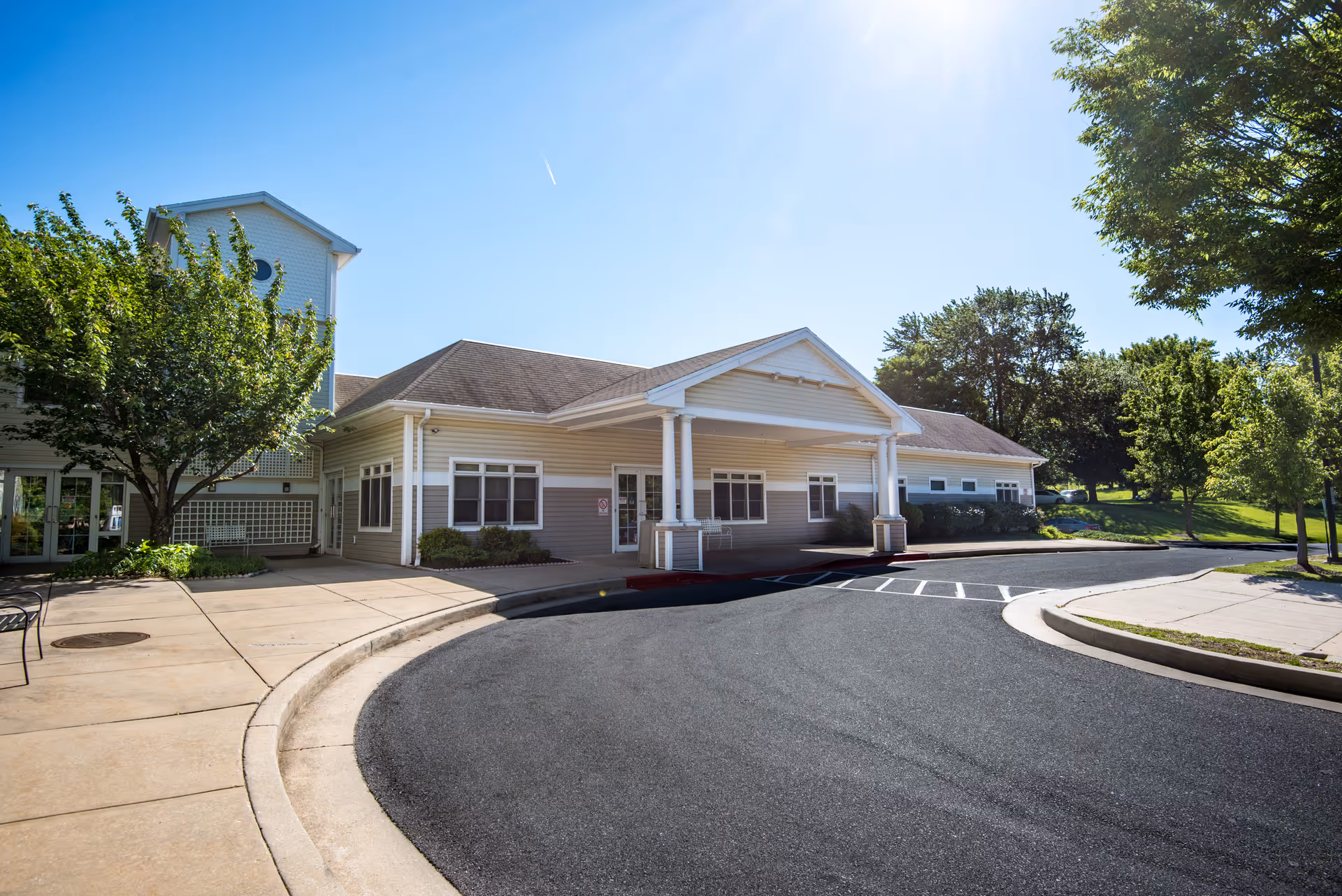 Exterior view of Westgate Hills Rehabilitation & Healthcare Center on a sunny day, showing the building entrance with a covered drop-off area, surrounding trees, and a curved driveway.