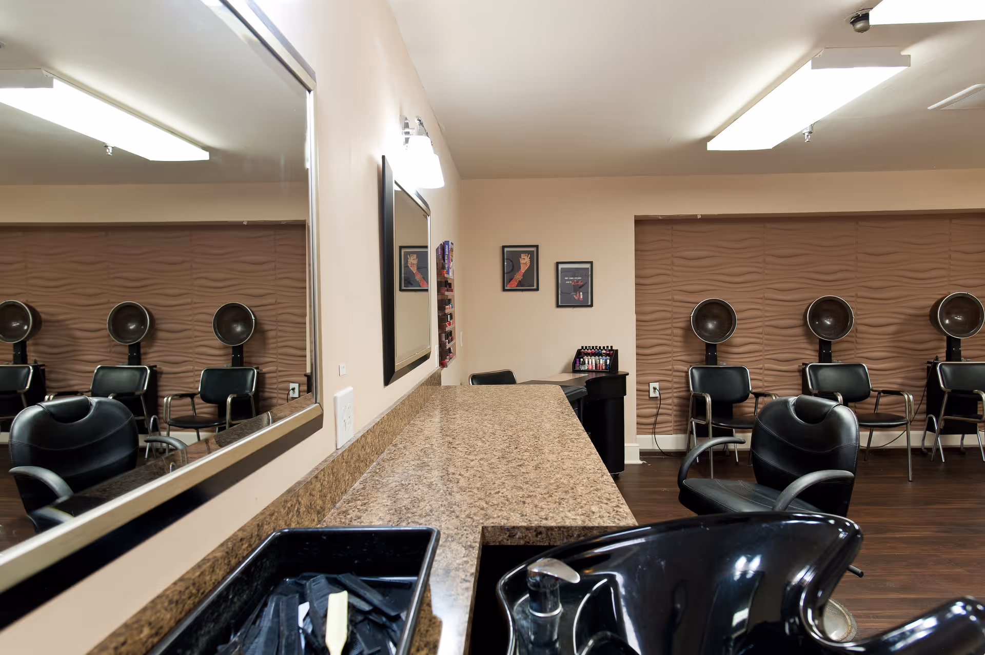 Interior salon with styling chairs, hooded hair dryers, mirrors, a shampoo sink, and a countertop.