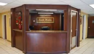 Wooden reception desk in a bright facility lobby with signage behind.