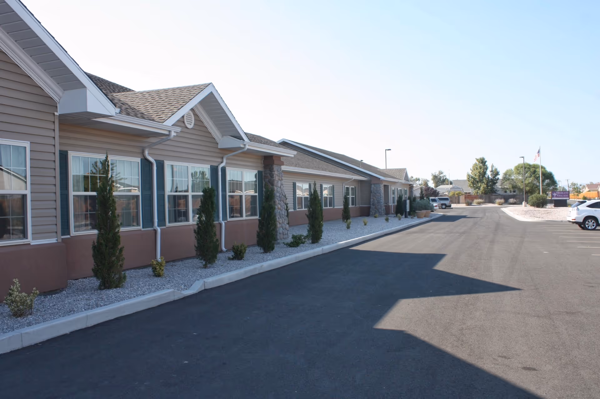 Exterior view of a single-story senior living building with windows, small landscaping, and an adjacent parking lot.