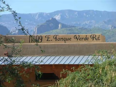 Exterior view of a building with a sign and desert mountains in the background.