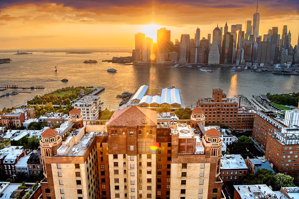 Aerial sunset view of Brooklyn Heights buildings with the Manhattan skyline across the water.