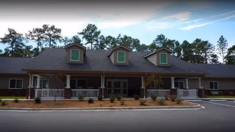 Front view of New Hanover House senior living facility with a long porch and trees.