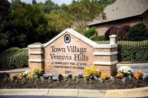 Brick entrance sign for Town Village Vestavia Hills with colorful flowers and shrubs.
