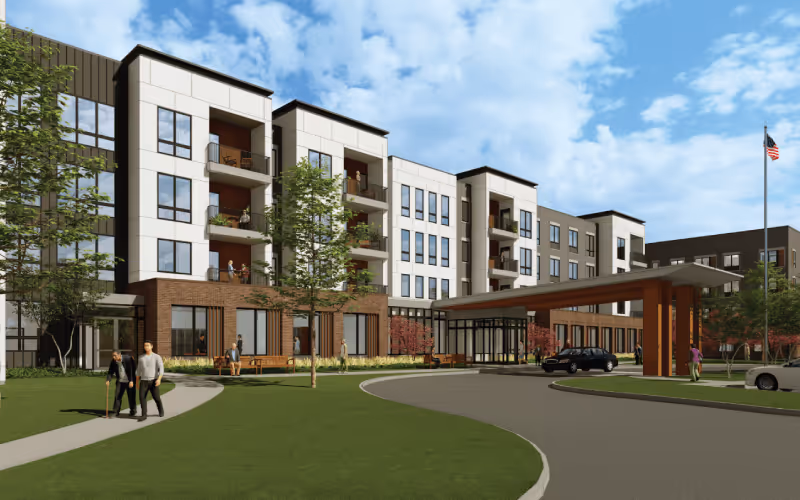 Modern three-story senior living building with a covered entrance and landscaped grounds.