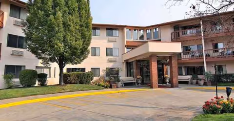 An exterior view of a multi-story senior living facility with a covered entrance.