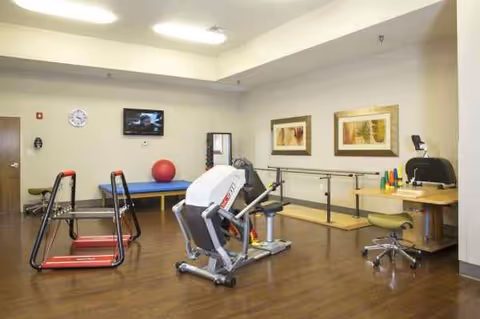 Interior fitness room in a senior facility with cardio machines, a ball, and workout equipment.