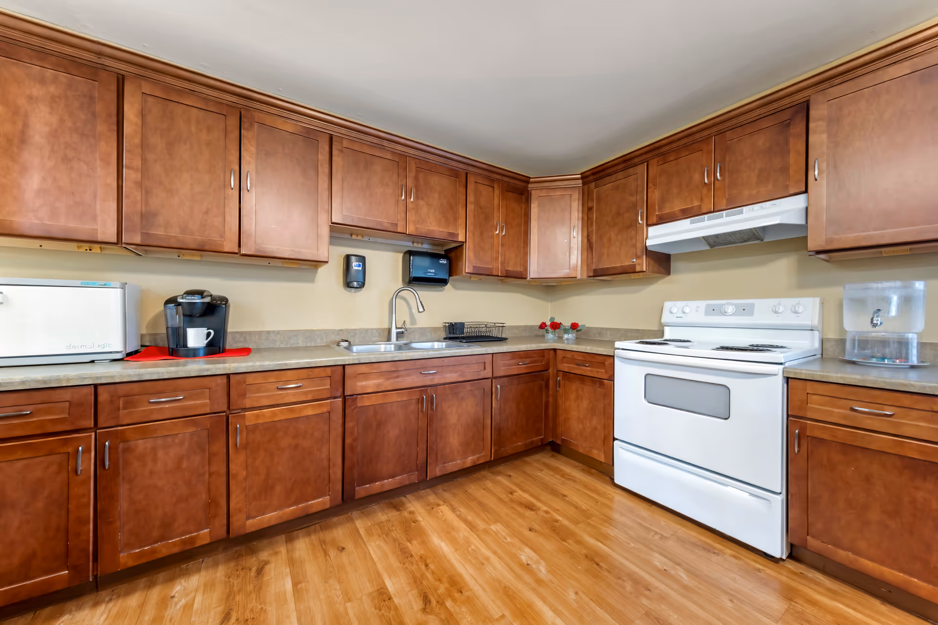 Kitchen with wooden cabinets, a white stove, sink, and countertop appliances.