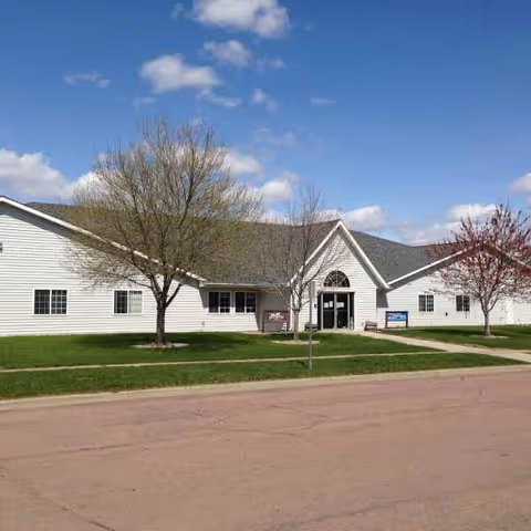 White, single-story assisted living facility with a front entrance and green lawn.