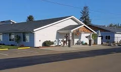 Exterior view of a single-story white building with a sloped roof and front porch.