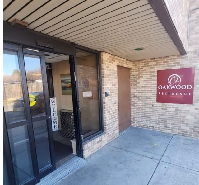 Exterior entrance of Oakwood Residence with glass doors and a maroon Oakwood sign.