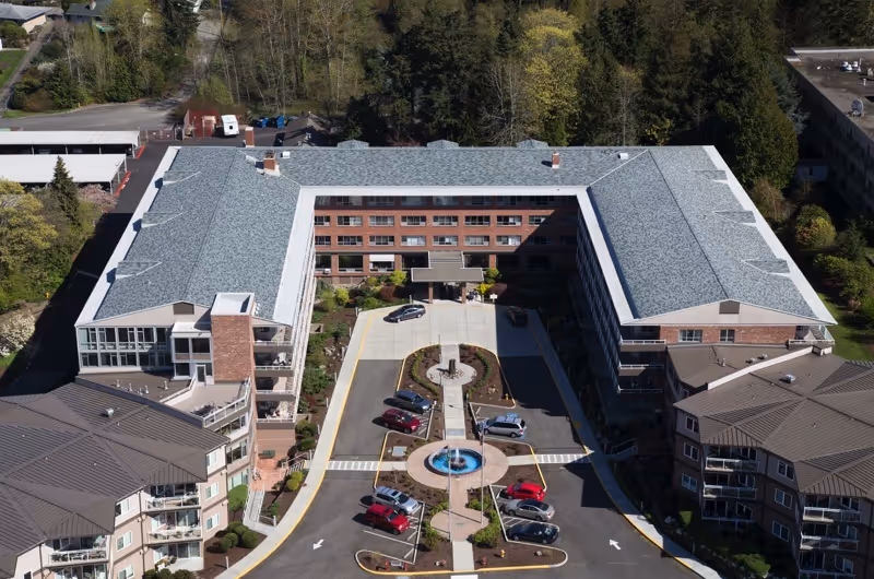Aerial view of Judson Park Retirement Community's U-shaped brick building with a central driveway, fountain, and parked cars.
