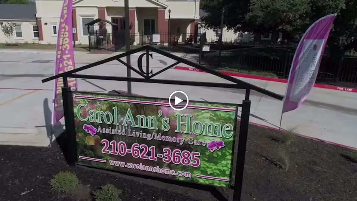 Front entrance sign reading "Carol Ann's Home Assisted Living/Memory Care" with a phone number displayed in front of the facility building.