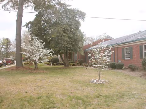 Exterior view of Emily Green Shores Assisted building with lawn and flowering trees
