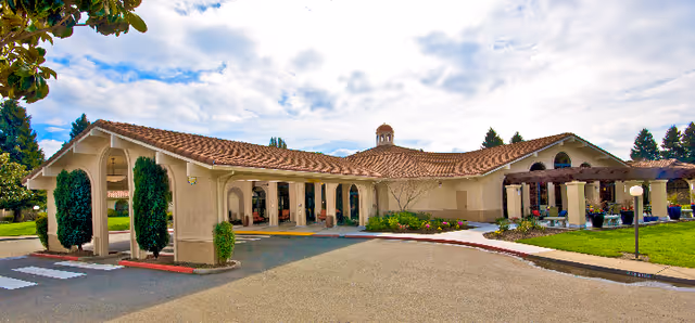 Front entrance of The Meadows of Napa Valley with an arched portico, red tiled roof, and landscaped driveway.