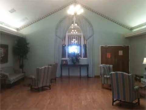A spacious lounge area with striped chairs, a small table, and a floral centerpiece.