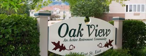Oak View retirement community sign surrounded by trees and hedges.
