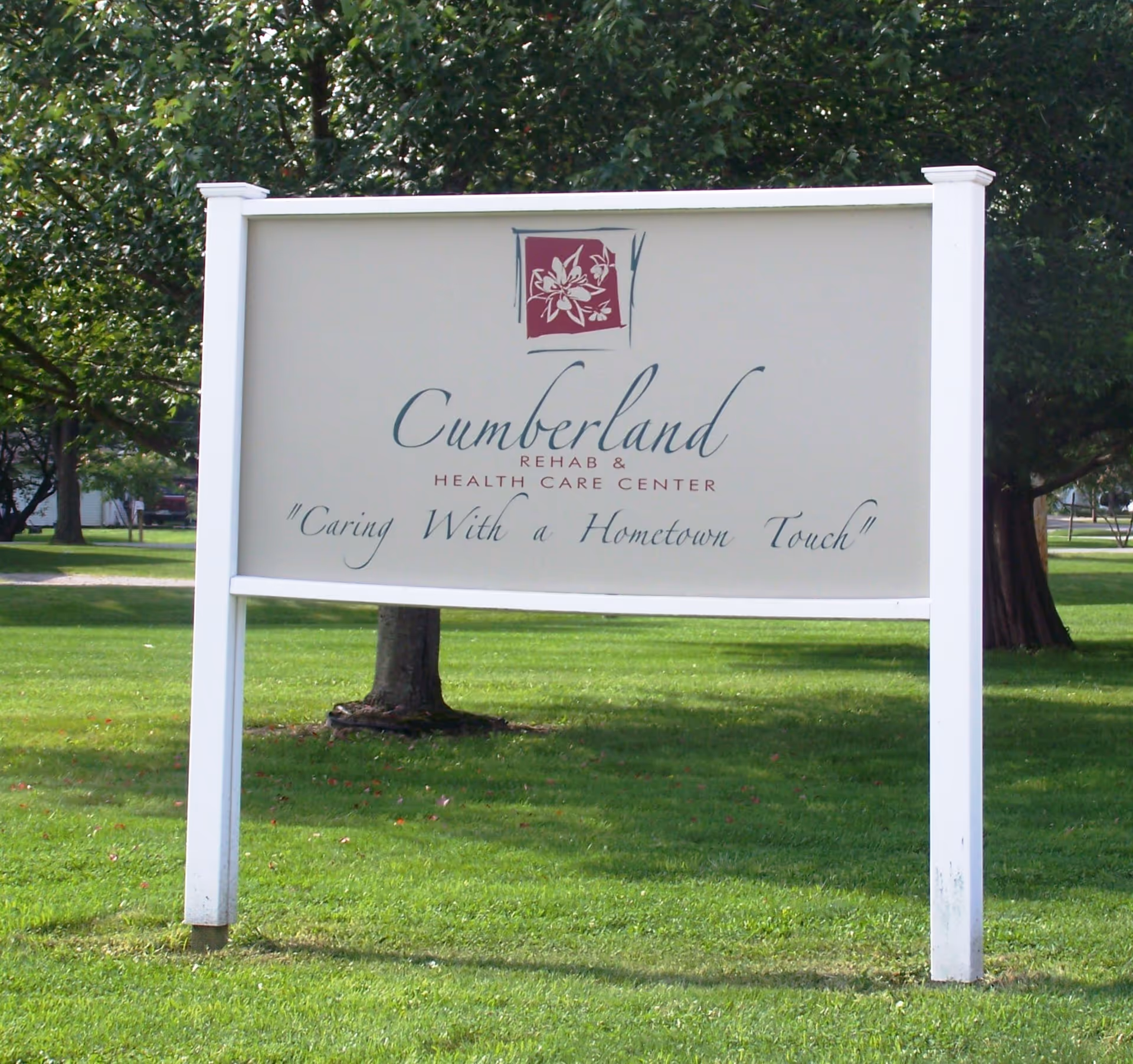 A freestanding sign on a grassy lawn reading "Cumberland Rehab & Health Care Center" with the tagline "Caring With a Hometown Touch."