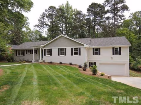 Front view of a single-story white house with a manicured lawn and attached garage.