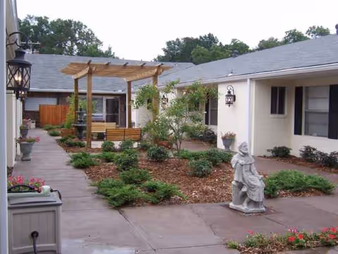 Care Center of Laurel courtyard features a wooden pergola, benches, shrubs, and a statue.