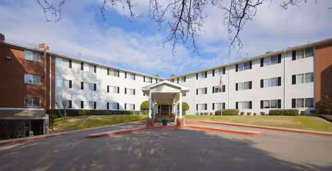 Front exterior view of Colonial Village senior living facility with a central entrance.