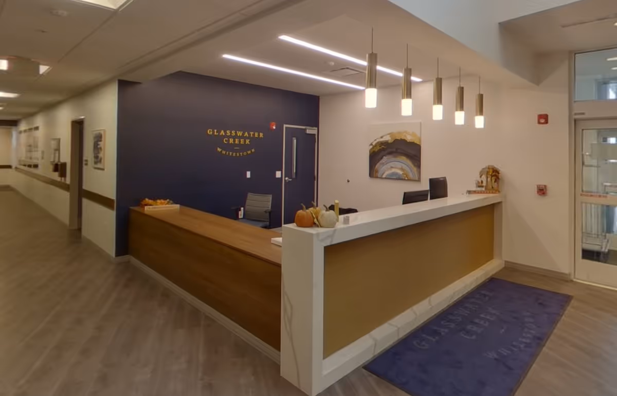 Reception desk and lobby area of Glasswater Creek of Whitestown with pendant lights and a blue feature wall.