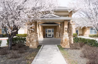 Entrance walkway to Emerson House at River Pointe, framed by flowering trees.