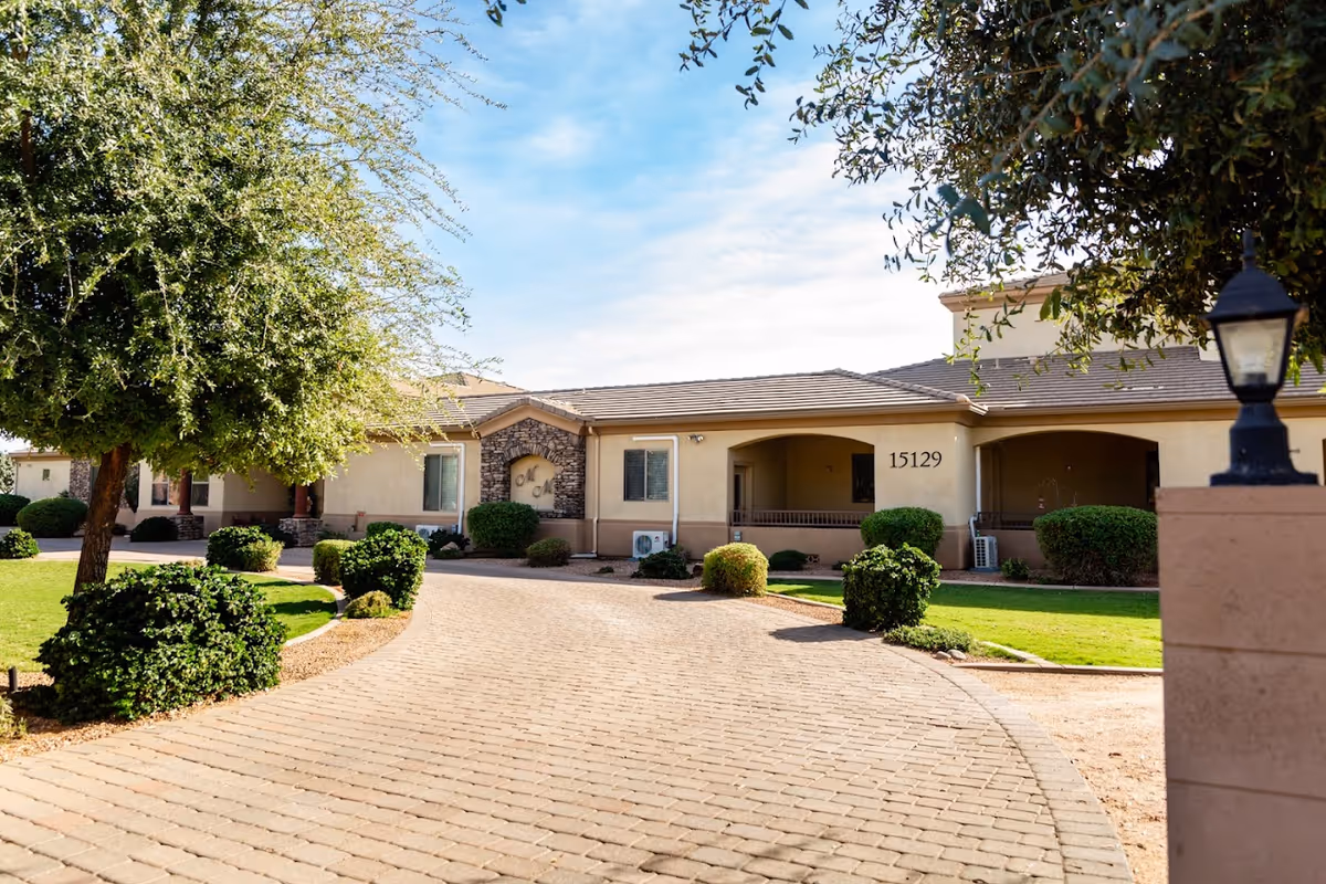 Curved brick driveway leads to Moonlight Manor's front exterior with manicured shrubs.