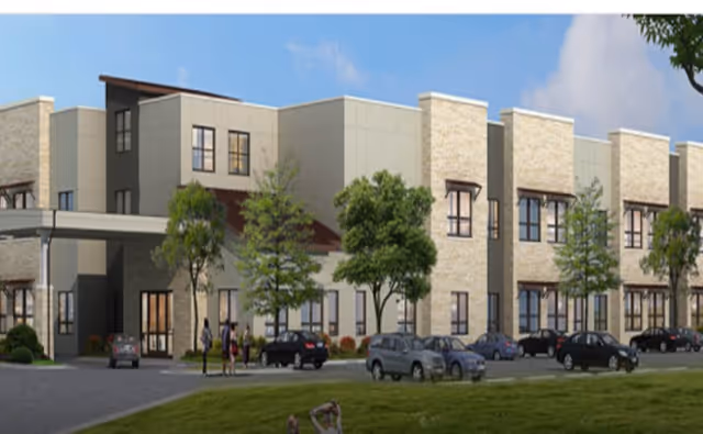 Modern two-story senior living building facade with parked cars and trees in front.