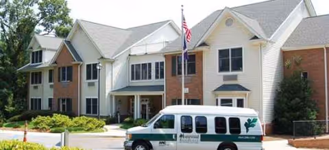 Exterior view of Kauhale Pettigru senior living facility with a white brick building and van.