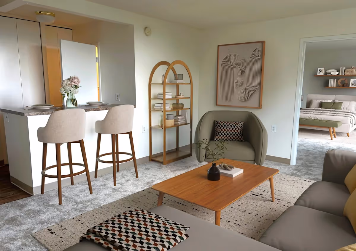 Bright living room in a senior facility with seating, a bar counter and stools, a wooden coffee table, a bookshelf, and an adjacent bedroom.
