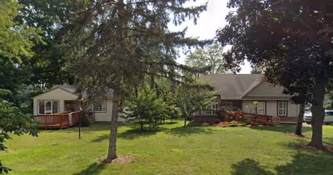 Exterior view of Deering Community Living with green lawn, trees, and porches.