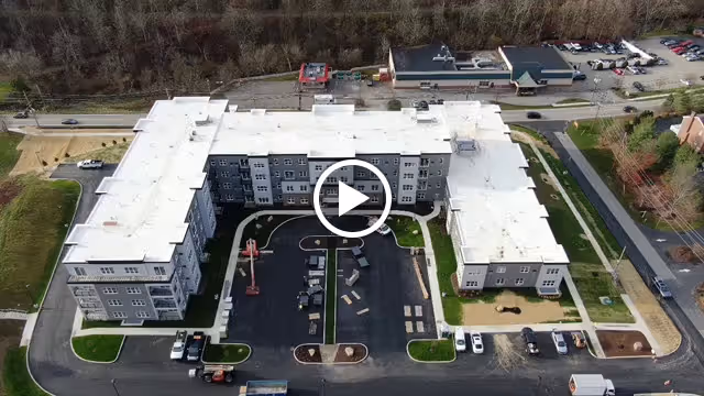 Aerial view of a large, U-shaped senior living facility named Ridgecrest of McMurray, surrounded by parking lots, roads, and some greenery with trees in the background.