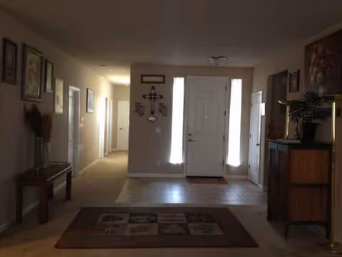 Bright entrance hall of Marigold Home with front door, rug, and hallway to rooms.