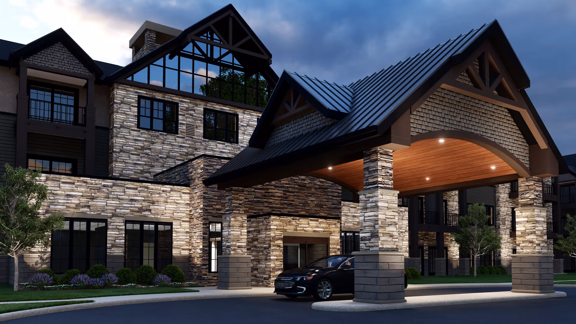 Exterior view of a modern senior living facility entrance at dusk, featuring stone and wood architectural elements, large windows, a covered drop-off area with a peaked roof supported by stone pillars, and a black car parked under the canopy.