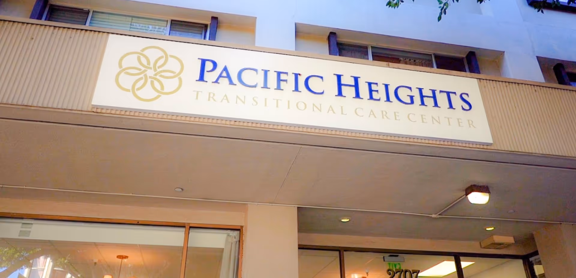 Exterior view of the Pacific Heights Transitional Care Center building showing the facility's sign with its name and logo above the entrance.