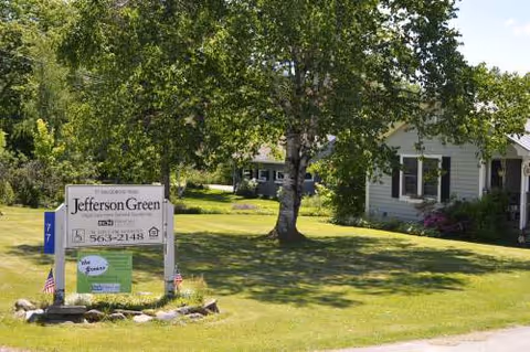 Jefferson Green sign on grassy lawn in front of a building with trees